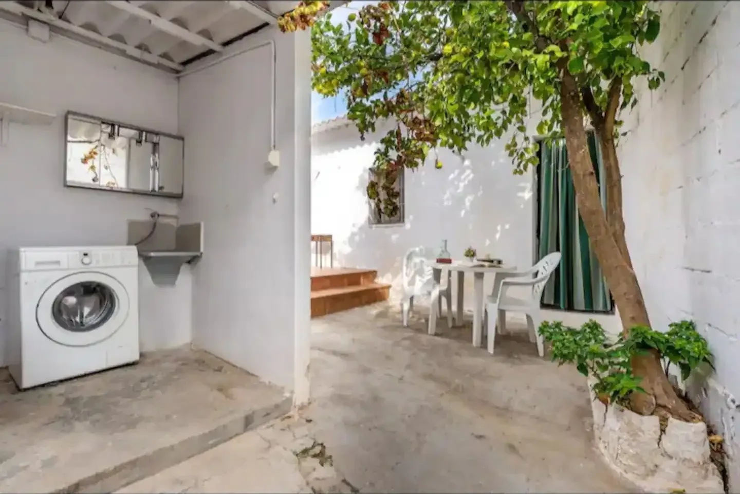 Cocina de la casa con lavadora, mesa y salida al patio