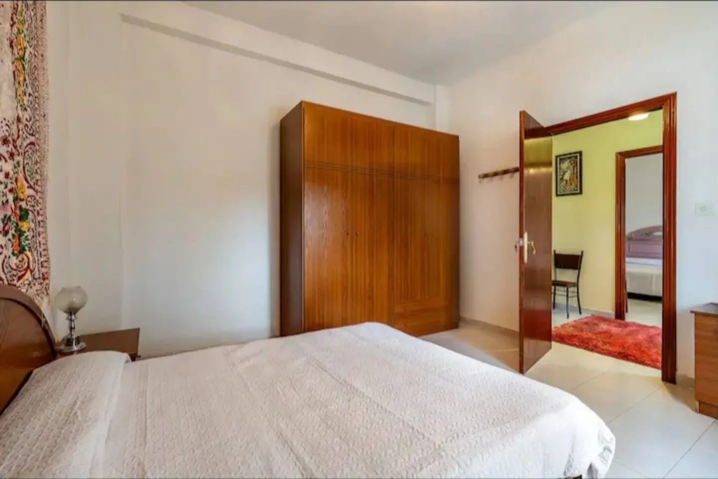 Dormitorio con cama de matrimonio, mesillas de madera y ventana al patio