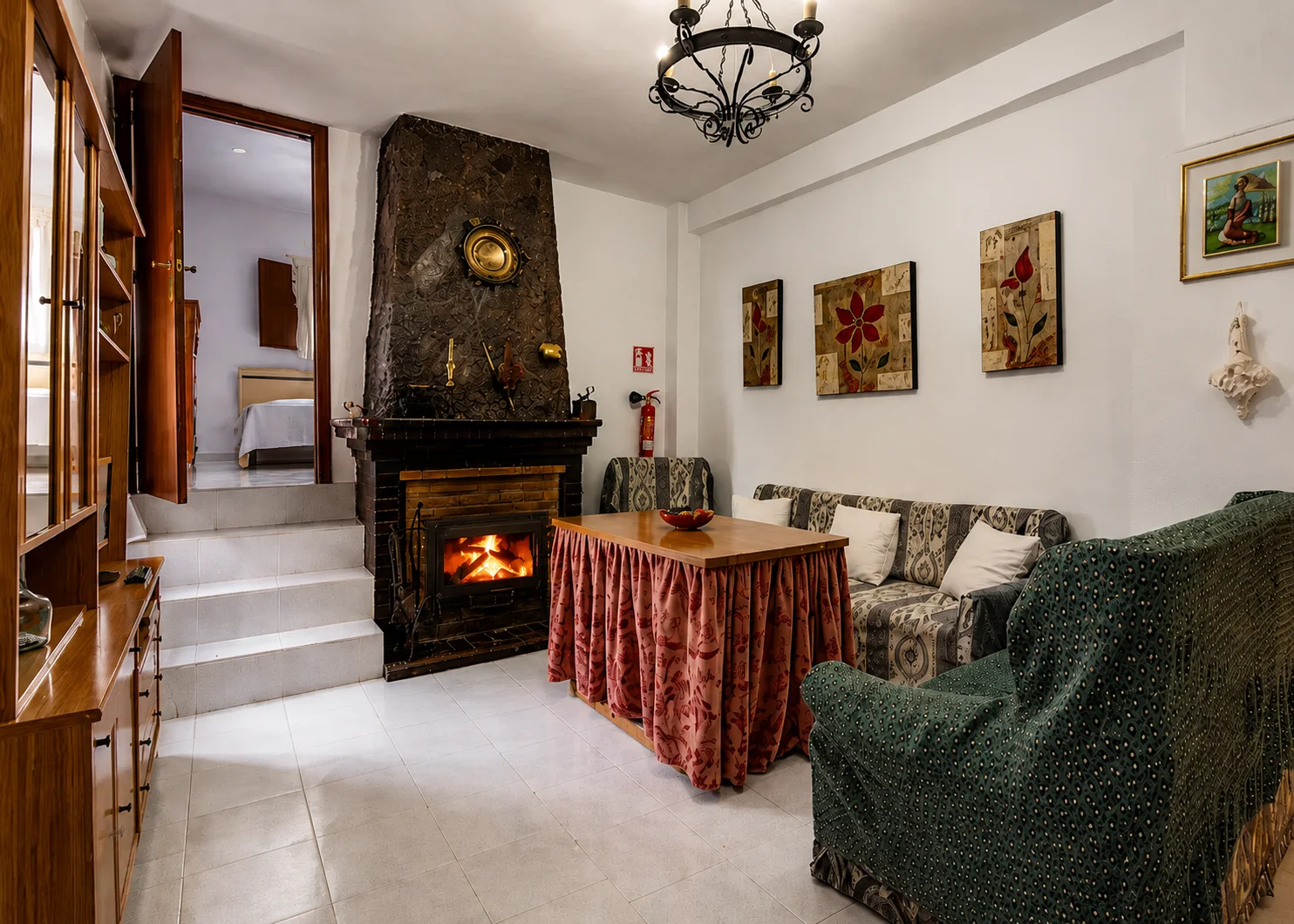 Comedor con la chimenea de leña encendida, sofás y mesa camilla